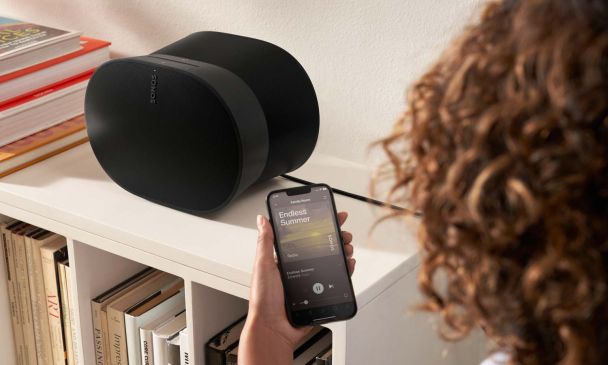 Woman using the sonos app to control her black speaker